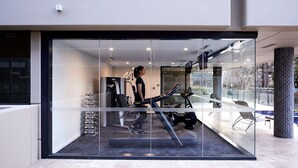 A modern gym with exercise equipment, large windows, and a glass wall. - Knightsbridge Canberra (Kingston)