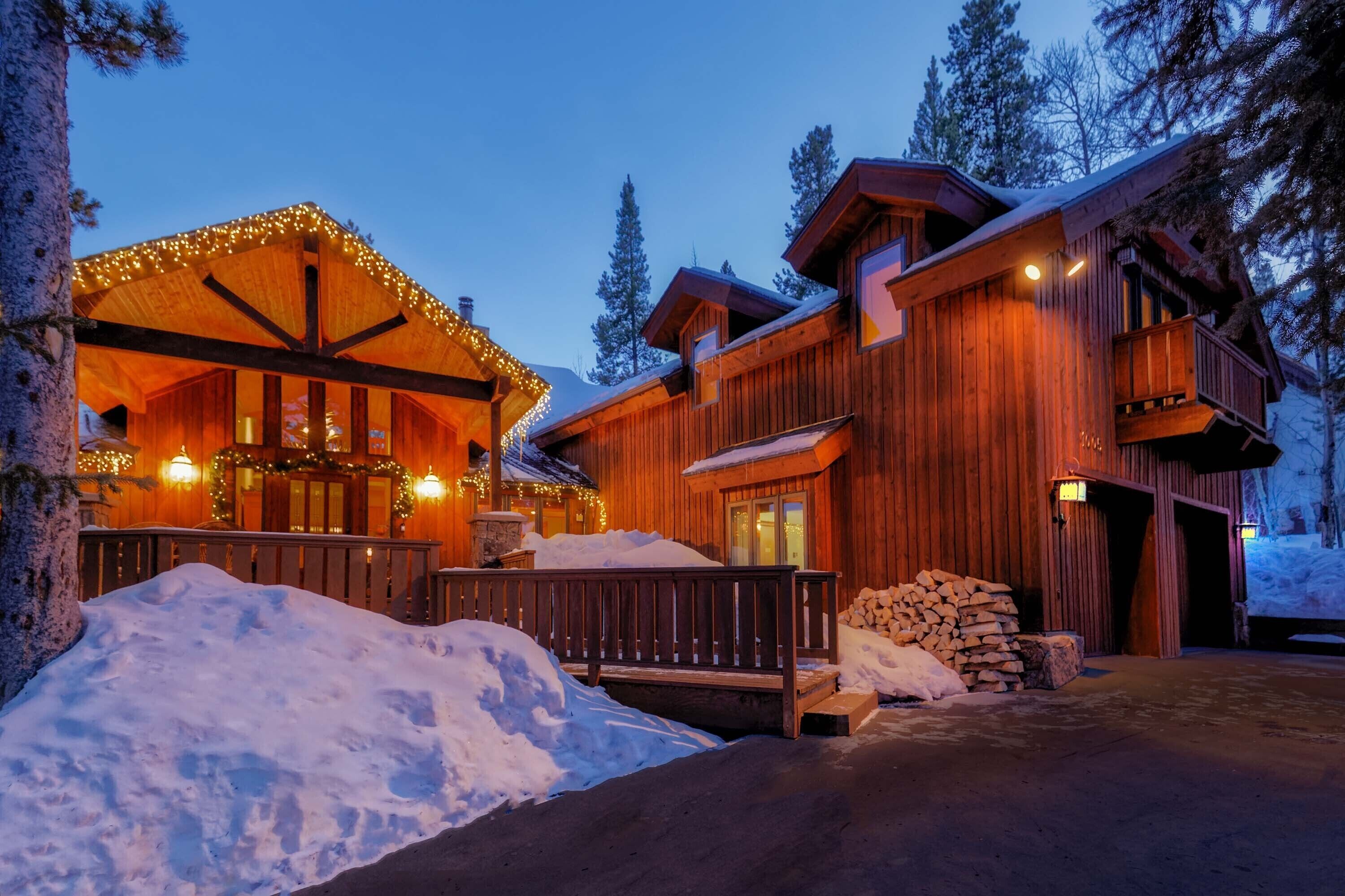 A wooden lodge with a covered porch and a stack of firewood.