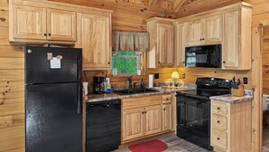Una cocina con armarios de madera, un refrigerador negro, una estufa y un microondas.