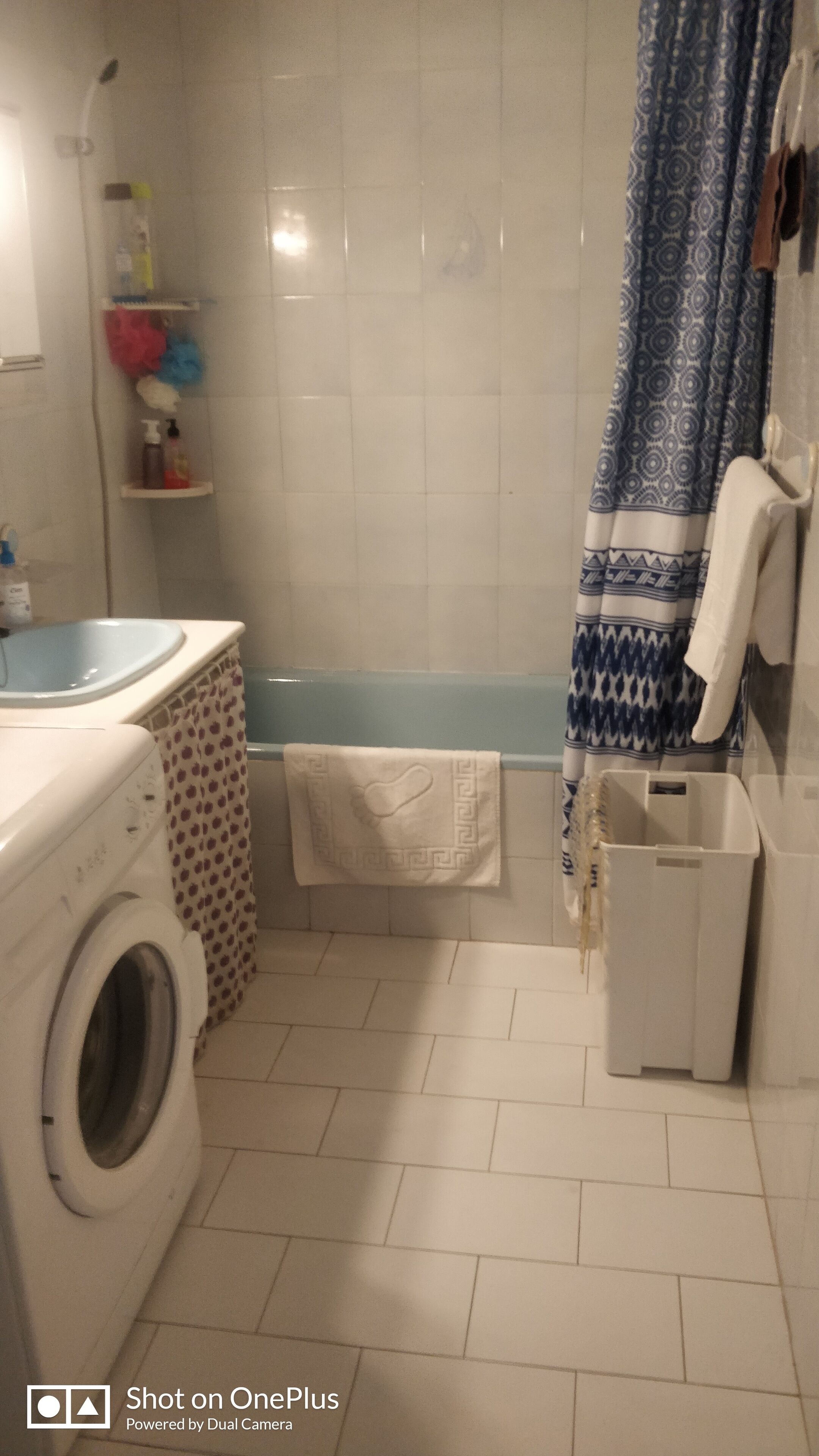 A bathroom with a washing machine, a bathtub, and a shower area.