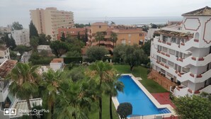 A residential area with a swimming pool, palm trees, and multi-story buildings.