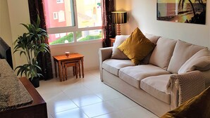 A living room with a sofa, a coffee table, a lamp, and a plant.