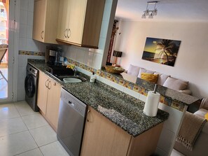 Una cocina compacta con lavadora, lavaplatos y encimera.