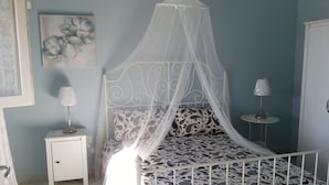 Une chambre à coucher avec un lit sous un dais, une table de chevet avec une lampe et un tableau mural.