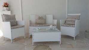 Un coin salon avec trois fauteuils en osier, une petite table et une plante en pot.