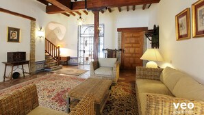 A cozy living room with wicker furniture, a wooden staircase, and a stone wall. - Casa Monsalves. 6 bedrooms, 5 bathrooms, patio (Sevilla)