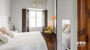 A bedroom with a bed, a chair, a lamp, a window, and a door. - Casa Monsalves. 6 bedrooms, 5 bathrooms, patio (Sevilla)