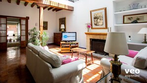 A spacious living room with a fireplace, a television, and a sofa. - Casa Monsalves. 6 bedrooms, 5 bathrooms, patio (Sevilla)