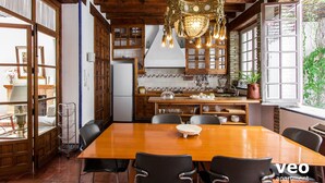 A spacious dining area with a wooden table and chairs, a chandelier, and a view of the kitchen and garden. - Casa Monsalves. 6 bedrooms, 5 bathrooms, patio (Sevilla)