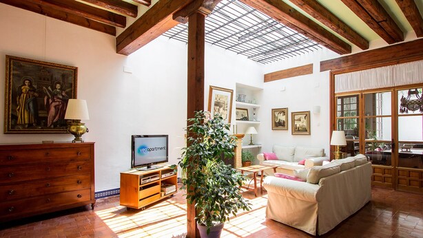 A living room with a TV, wooden furniture, a potted plant, and a painting on the wall. - Casa Monsalves. 6 bedrooms, 5 bathrooms, patio (Sevilla)
