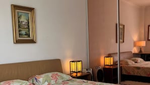 Une chambre d’hôtel avec un lit, une table de chevet avec une lampe, une armoire et un tableau encadré au mur.