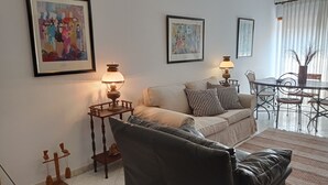 Un salon avec un canapé, deux lampes, une table et des chaises.