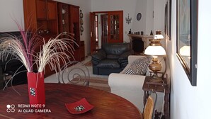 Un salon avec un canapé, une table à manger agrémentée d’un vase, une lampe et un meuble en bois.