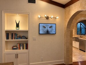 A modern kitchen with a stone archway, a built-in bookshelf with decorative items, and a wall-mounted light fixture. - Bachelor  Party HQ, pickleball/golf, 16 beds. DT (Austin)