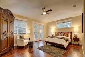 Une chambre à coucher comprenant un lit, une chaise, une armoire, un ventilateur de plafond et une fenêtre.