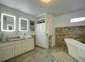 A modern bathroom with a large mirror, a bathtub, and a stone wall. - Bachelor Pad 18 beds, Golf, Pool, Pickleball, 5min to 6th street (Austin)