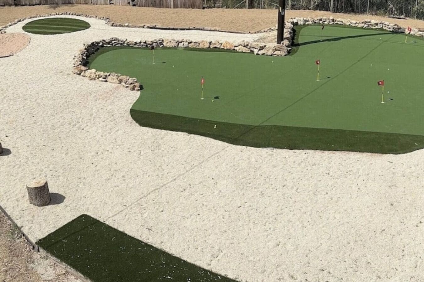 Ein Minigolfplatz mit Sandfällen, einer gepflegten Putting-Fläche und einer Steingrenze.