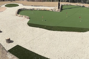 A miniature golf course with sand traps, a green putting area, and a stone border. - Bachelor Pad 18 beds, Golf, Pool, Pickleball, 5min to 6th street (Austin)