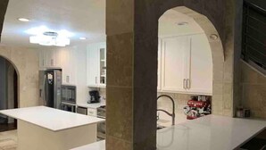Una cocina moderna con encimeras blancas, horno empotrado y fregadero.