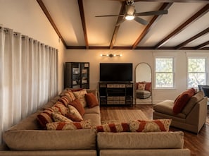 A living room with a sectional sofa, a television, and a ceiling fan. - Bachelor  Party HQ, pickleball/golf, 16 beds. DT (Austin)