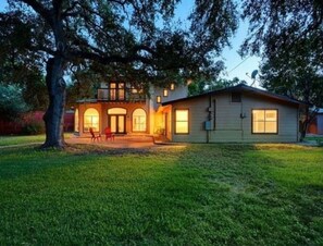 A two-story house with a front porch, a garage, and a well-maintained lawn. - Bachelor  Party HQ, pickleball/golf, 16 beds. DT (Austin)