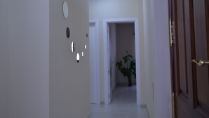 A hallway with a potted plant, a door, and a light fixture on the wall. - CASA YOEL "PRIVACY, WARMTH, GUARANTEED REST, IDEAL FOR FAMILIES, NEW !!! (Granadilla)
