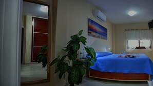 A bedroom with a bed, a potted plant, a painting, and a window with curtains. - CASA YOEL "PRIVACY, WARMTH, GUARANTEED REST, IDEAL FOR FAMILIES, NEW !!! (Granadilla)