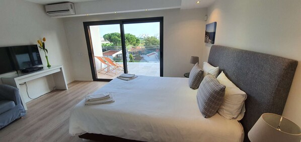 Ein Hotelzimmer mit Bett, Fernseher, Schreibtisch, Stuhl und Blick ins Freie.