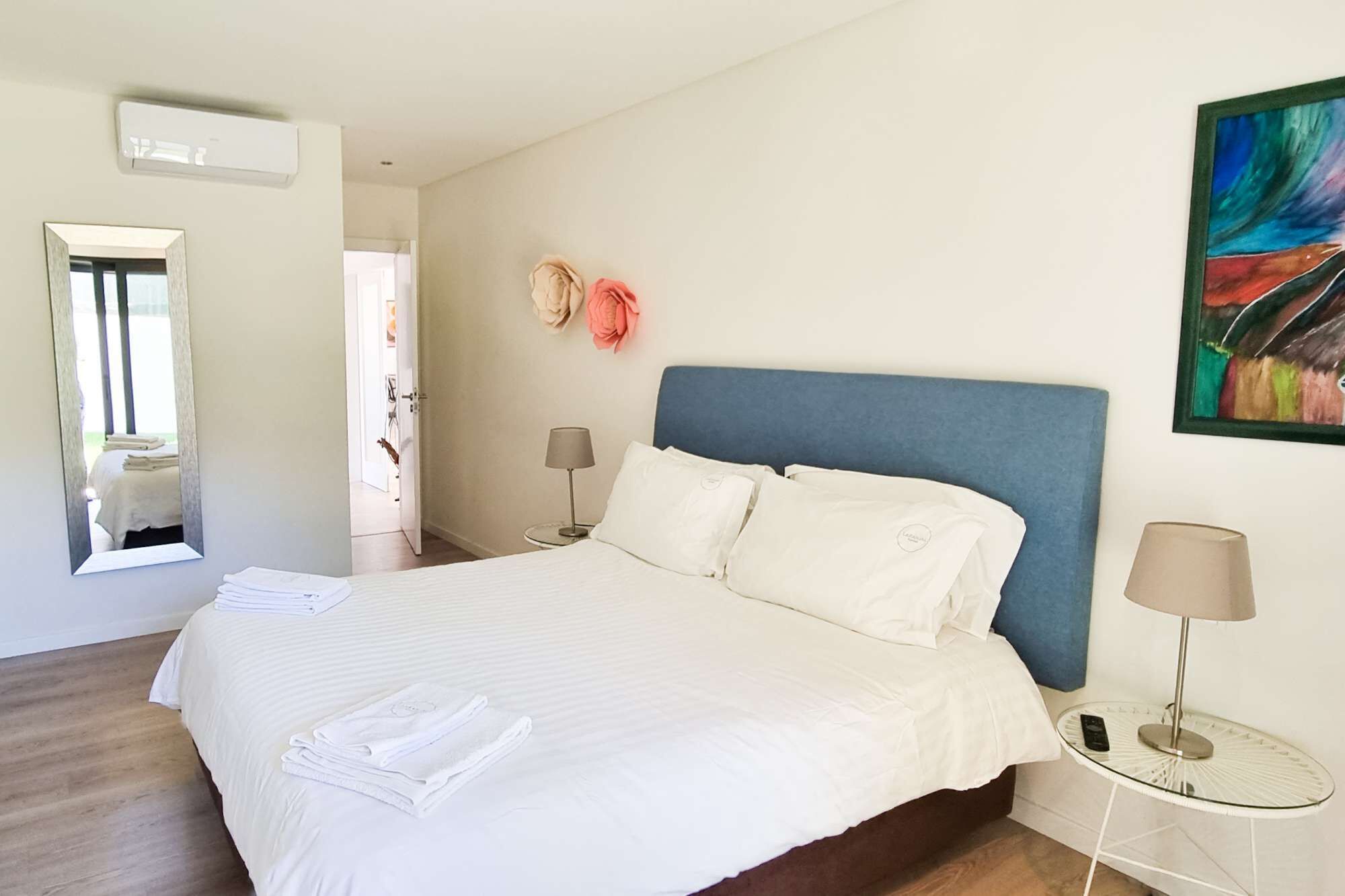 Una camera d'albergo con un letto grande, due comodini, uno specchio e un quadro appeso al muro.