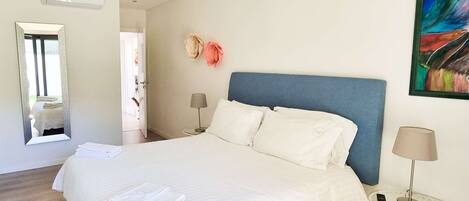 Una camera d'albergo con un letto grande, due comodini, uno specchio e un quadro appeso al muro.