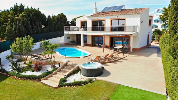 Una casa moderna de dos pisos con piscina, mobiliario exterior y bañera de hidromasaje.