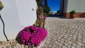 Una calle adoquinada con un edificio blanco a la izquierda y una maceta a la derecha.