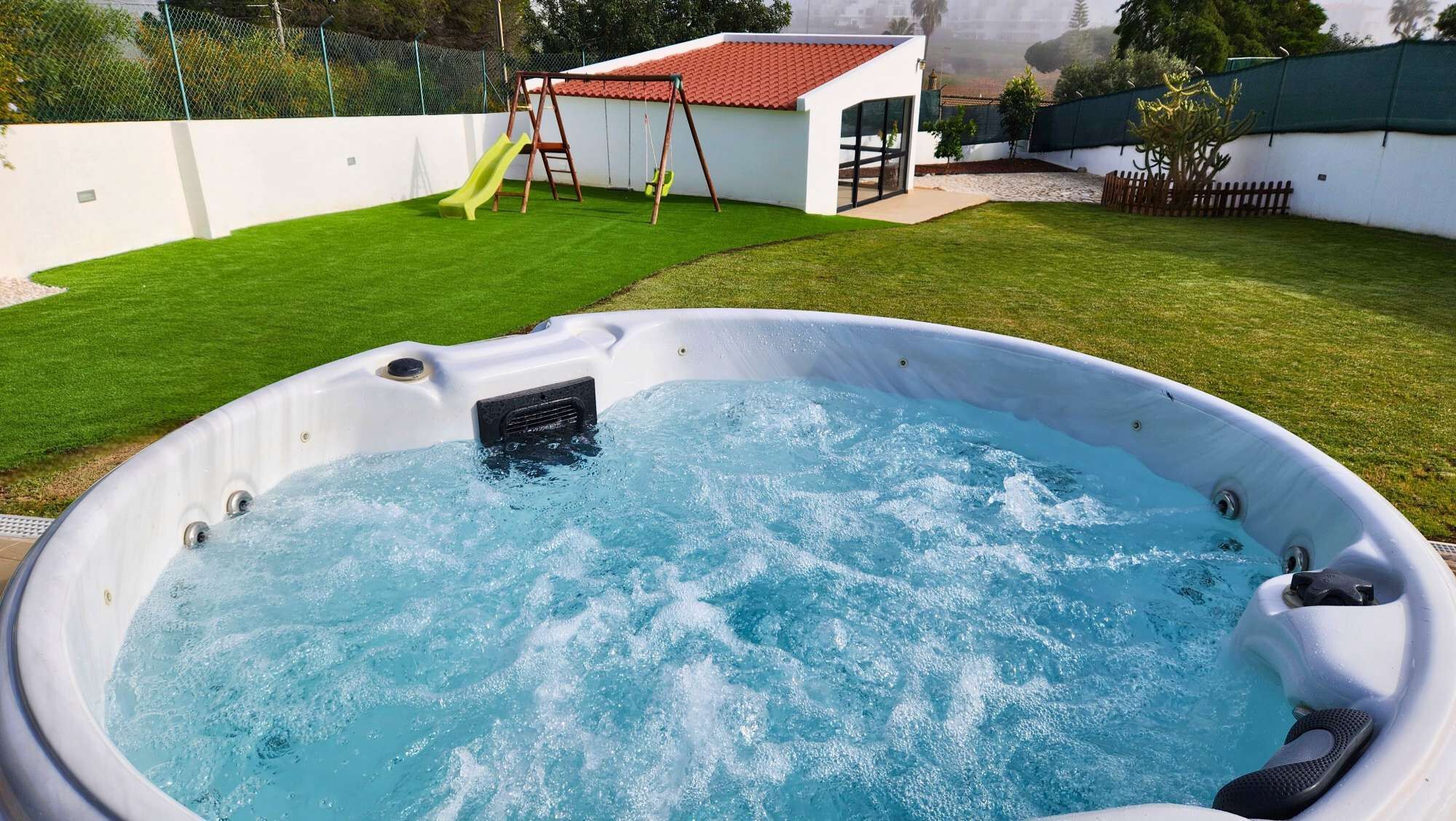 Un jacuzzi en un patio trasero con un tobogán y un columpio.