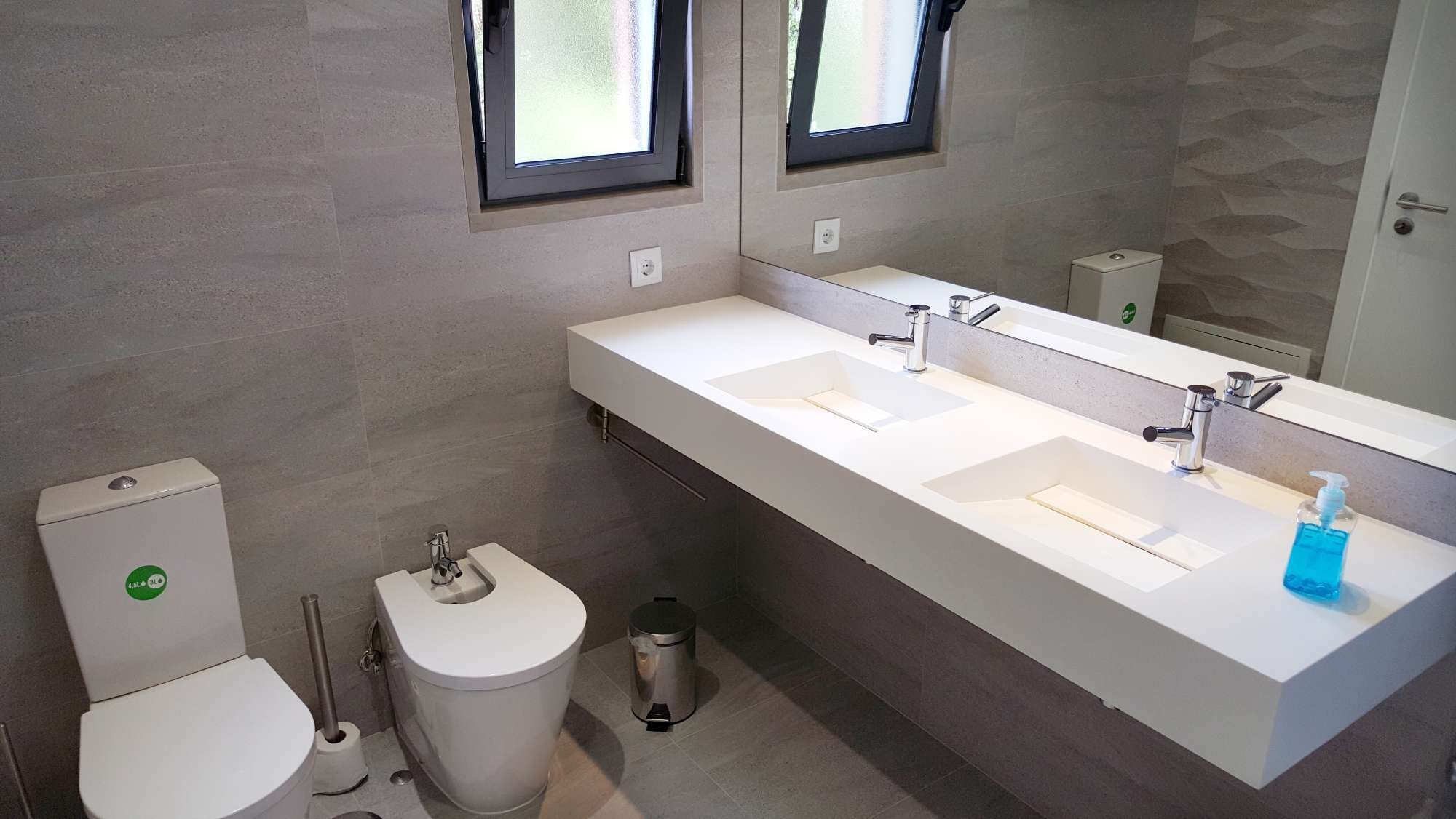 Ein modernes Badezimmer mit zwei Waschbecken, einer Toilette und einem Mülleimer.