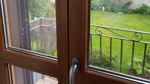 Une porte en bois avec une poignée en métal, qui donne sur un balcon doté d’une balustrade en métal.