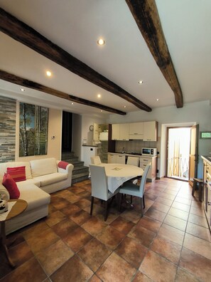 A modern living room with a sofa, dining table, and kitchen area. - Pella: House / Villa - Pella (Pella)