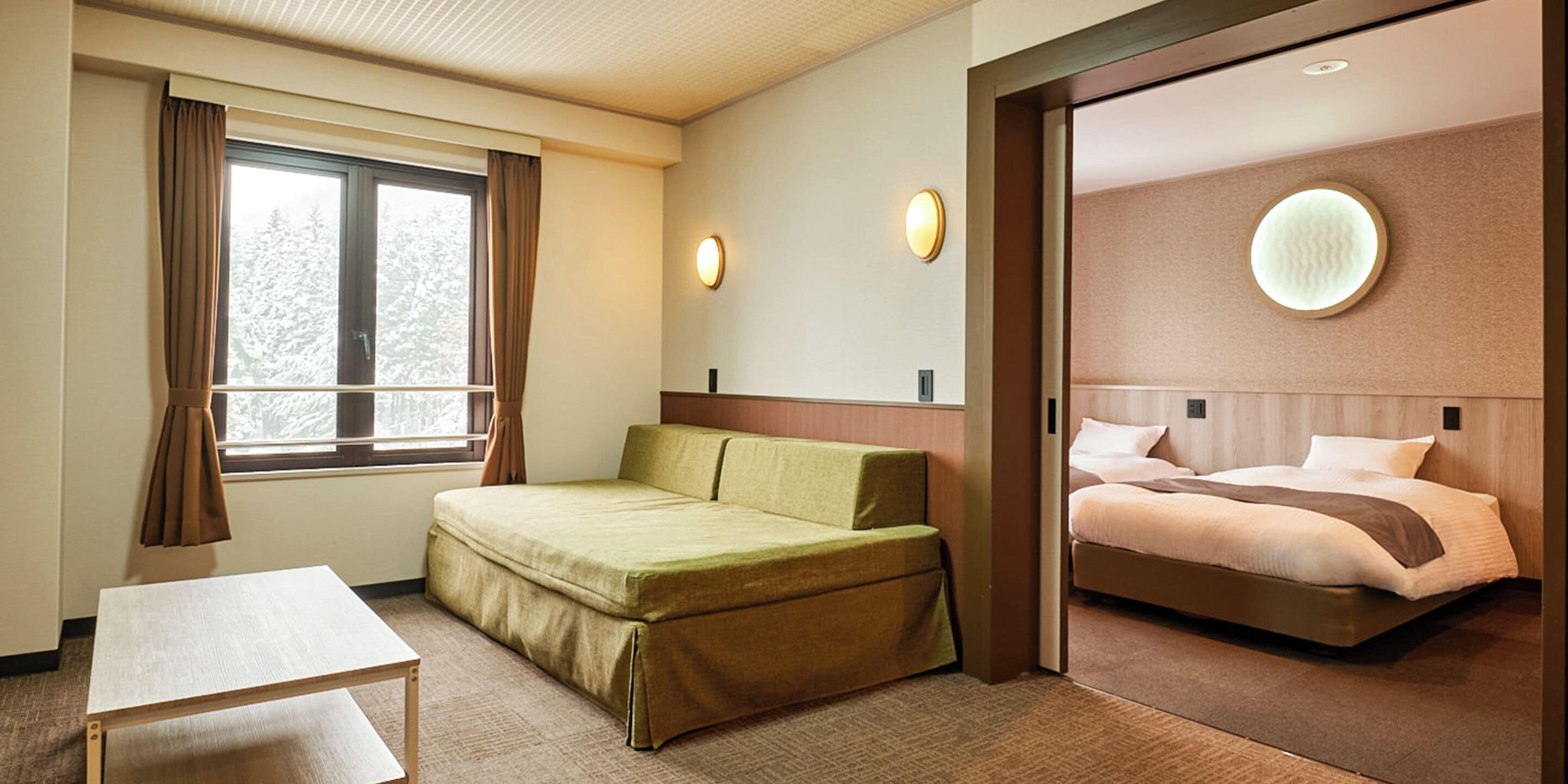 Une chambre d’hôtel avec un lit, un canapé, une table et une fenêtre avec des rideaux.