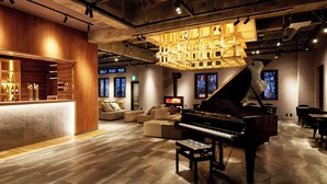 A spacious lobby with a grand piano, a bar area with shelves of bottles, and a cozy seating area with a fireplace. - Hotel Abest Happo Aldea (Hakuba)