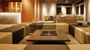 A modern lounge area with leather sofas, a central coffee table, and a bar area with shelves of bottles. - Hotel Abest Happo Aldea (Hakuba)