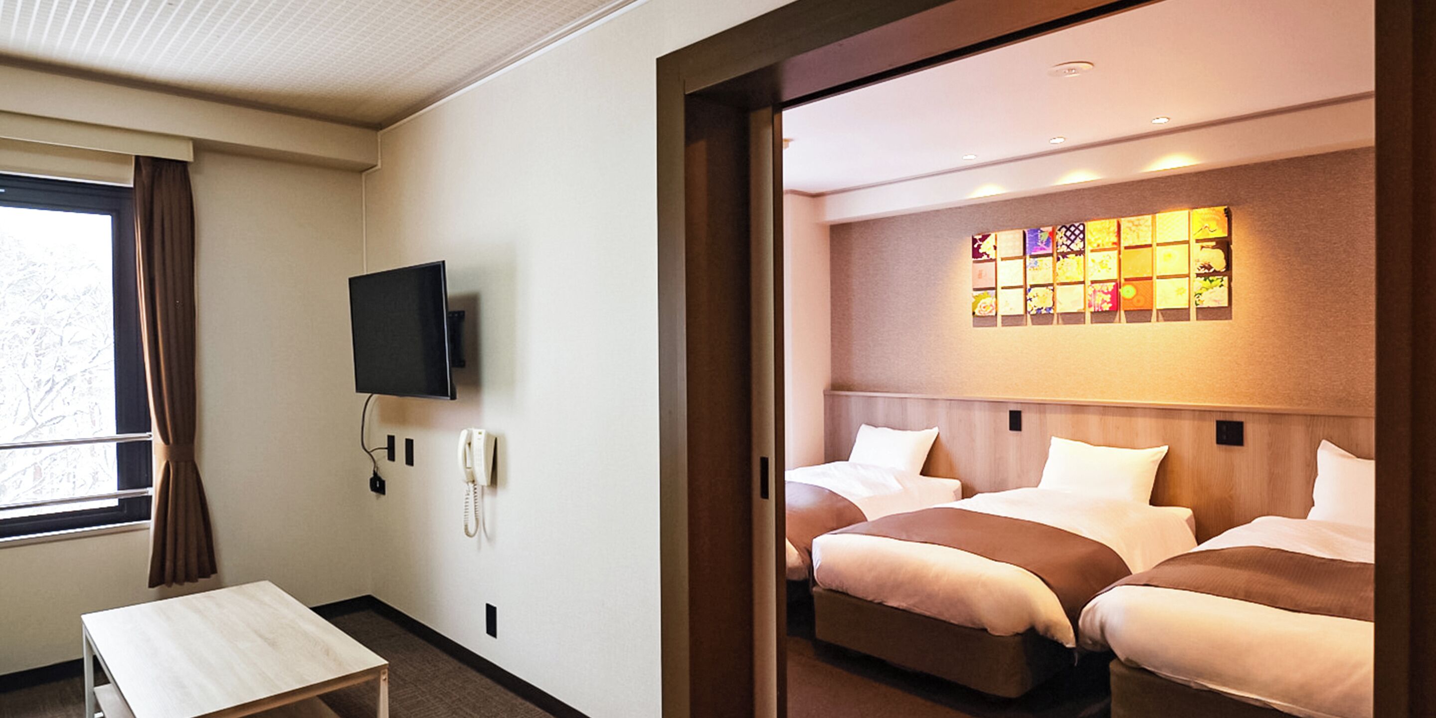 A hotel room with two beds, a TV, a phone, and a window with curtains.