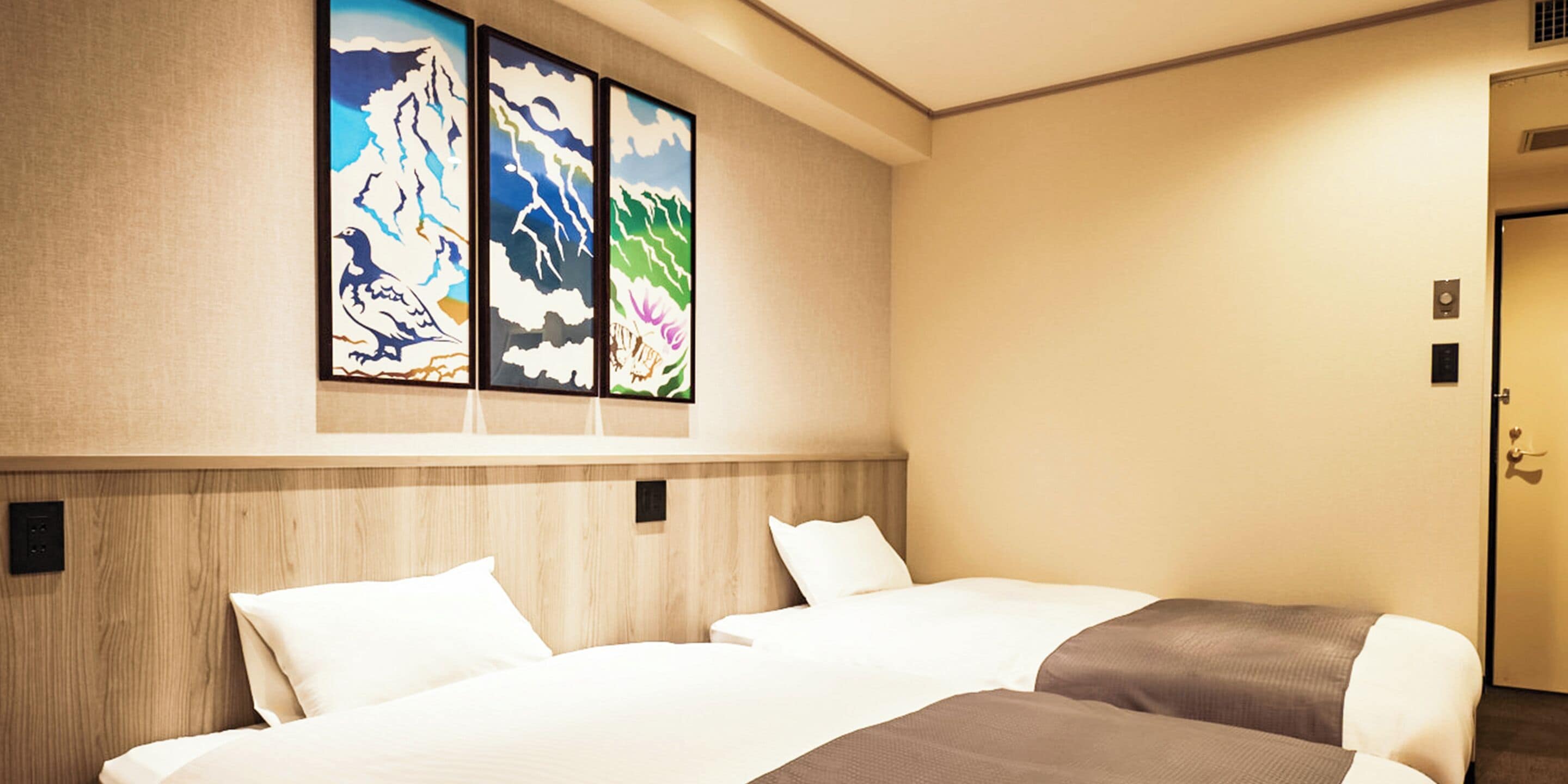 A hotel room with two beds, a wooden headboard, and a wall with abstract art.
