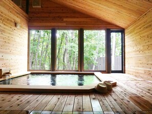 A wooden cabin with a hot tub and large windows overlooking a forest. - Hotel Abest Happo Aldea (Hakuba)