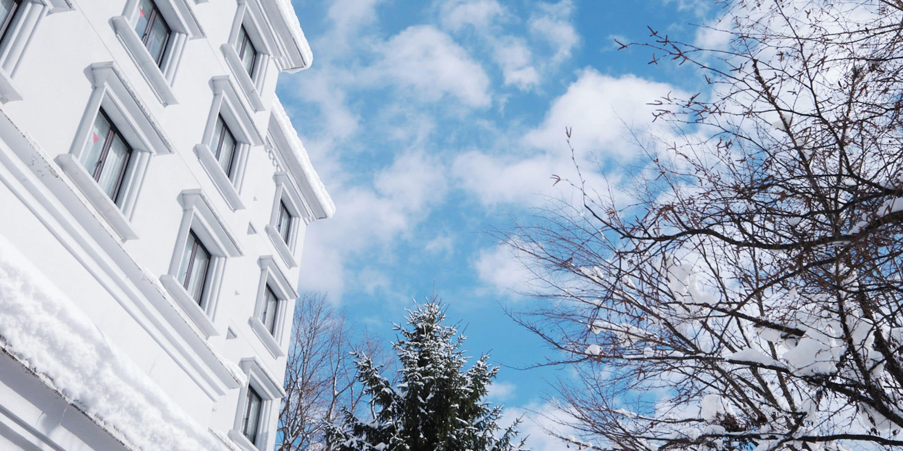 A white building with multiple windows and a clear sky with clouds.