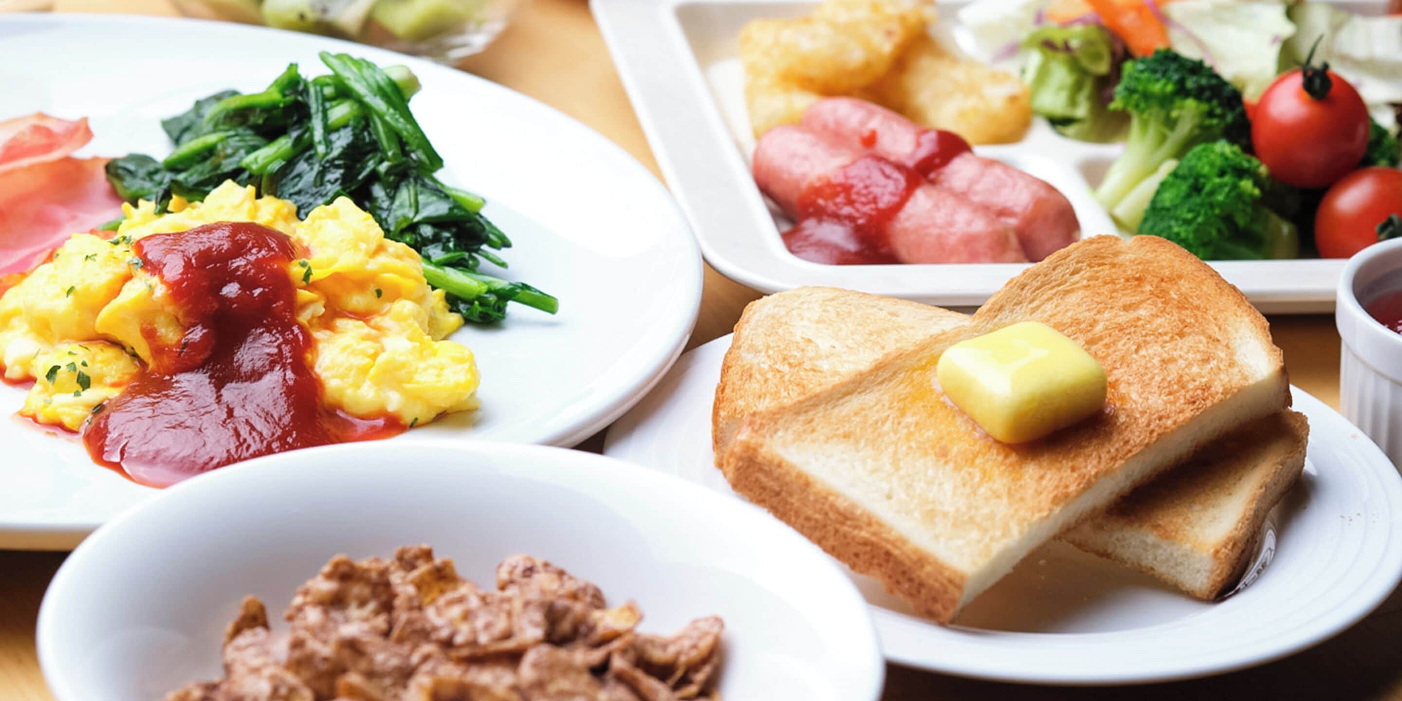 Een ontbijtbuffet met roerei, toast en diverse groenten.
