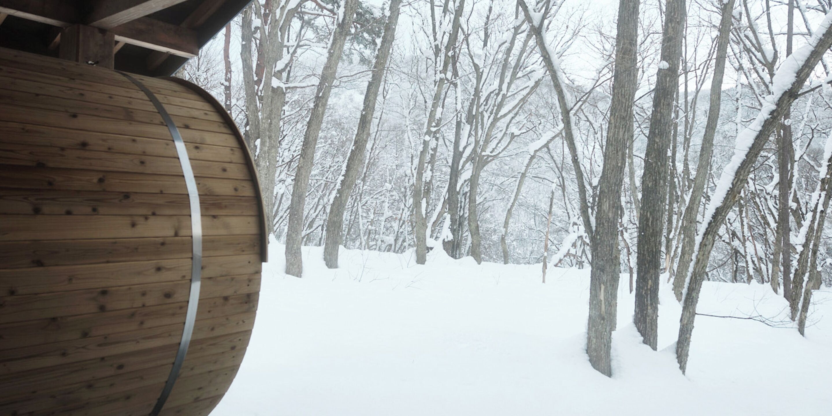A wooden barrel structure in a snowy forest.