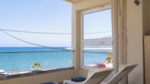 Ein Balkon mit Meerblick, ein Stuhl, ein Handtuch und ein kleiner Tisch.