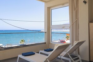 A balcony with a view of the sea, a chair, a towel, and a small table.