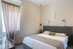 A hotel room with a bed, a desk, and a chair.