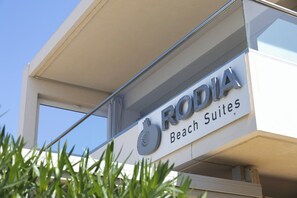 Ein Schild für 'RODIA Beach Suites' mit einem Logo über dem Schriftzug.