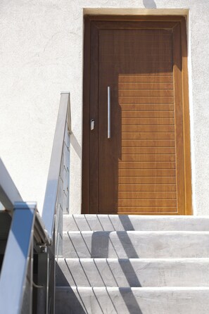 A wooden door with a handle, set in a white wall with a textured surface.
